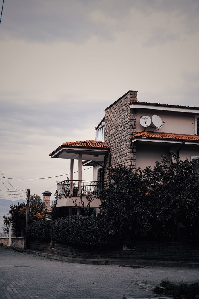 A charming house with a red roof surrounded by greenery in İzmit, Kocaeli, Turkey, under a cloudy sky.